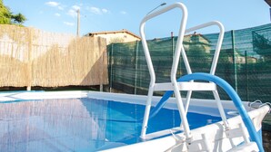 Una piscina con una escalera blanca y una manguera azul.