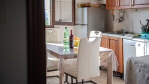 Una cocina con una mesa, sillas, un refrigerador, un lavamanos y armarios.