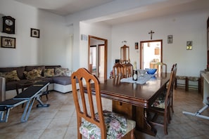 Un coin repas avec une table en bois, des chaises, un banc et une horloge au mur.