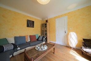 Ein Wohnzimmer mit einer Couch, einem Couchtisch mit einer Kaffeetasse und einem Teekessel, einem Schrank und einer Tür.