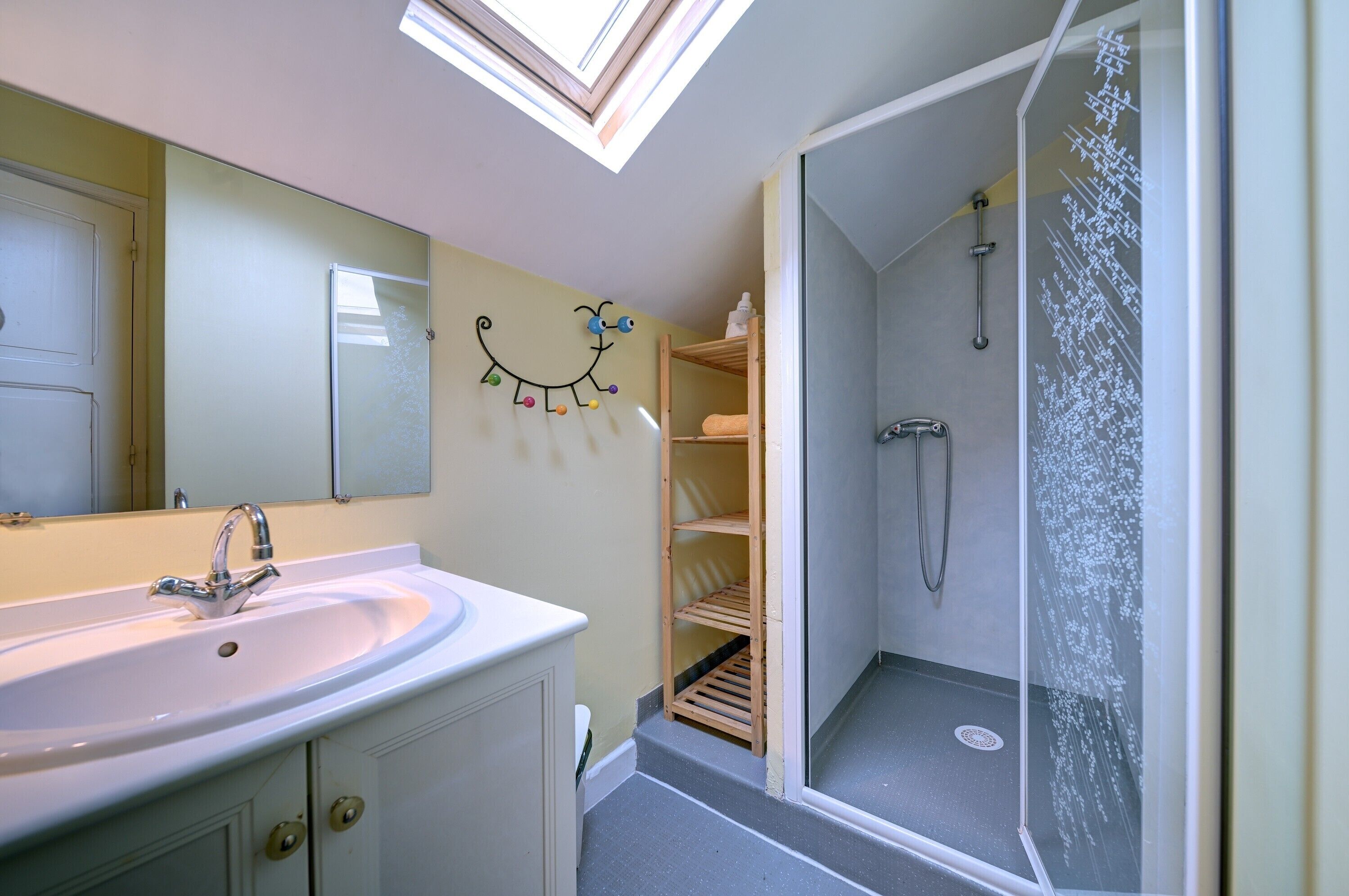 Ein Badezimmer mit Oberlicht, Waschbecken, Dusche und Ablagefläche.