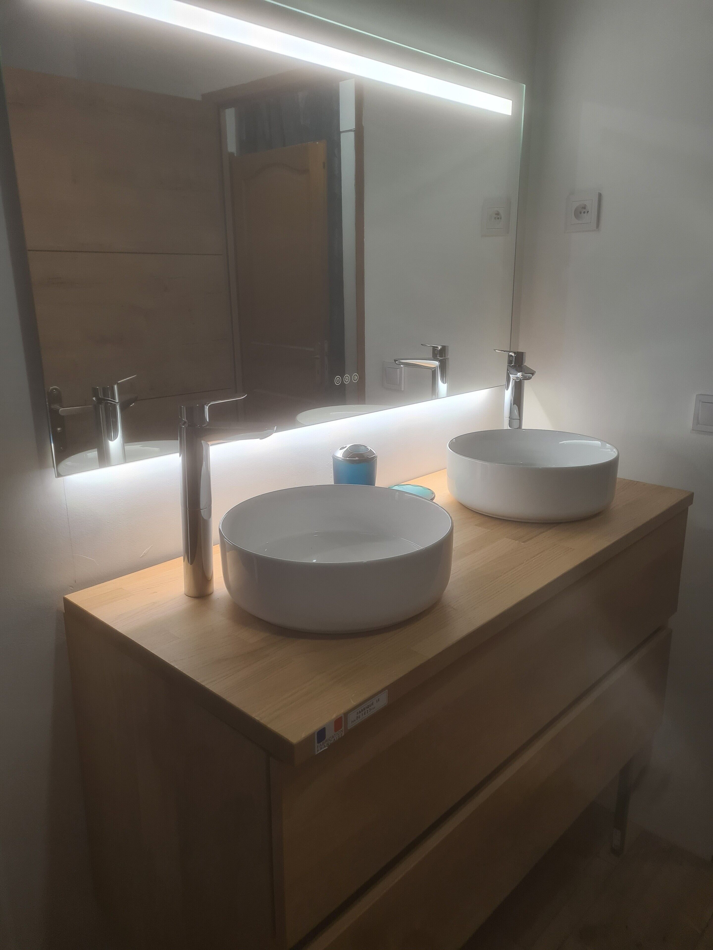 Un baño con dos lavamanos, un espejo y una lámpara sobre el espejo.