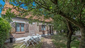 A brick building with a garden area, outdoor seating, and a pathway. - Entre terre et mer,la campagne à 700 m de la plage (Oye-Plage)