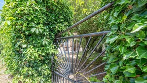 A metal spiral staircase surrounded by dense green foliage. - Entre terre et mer,la campagne à 700 m de la plage (Oye-Plage)
