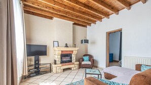 A living room with a fireplace, a television, a sofa, and a chair. - Entre terre et mer,la campagne à 700 m de la plage (Oye-Plage)
