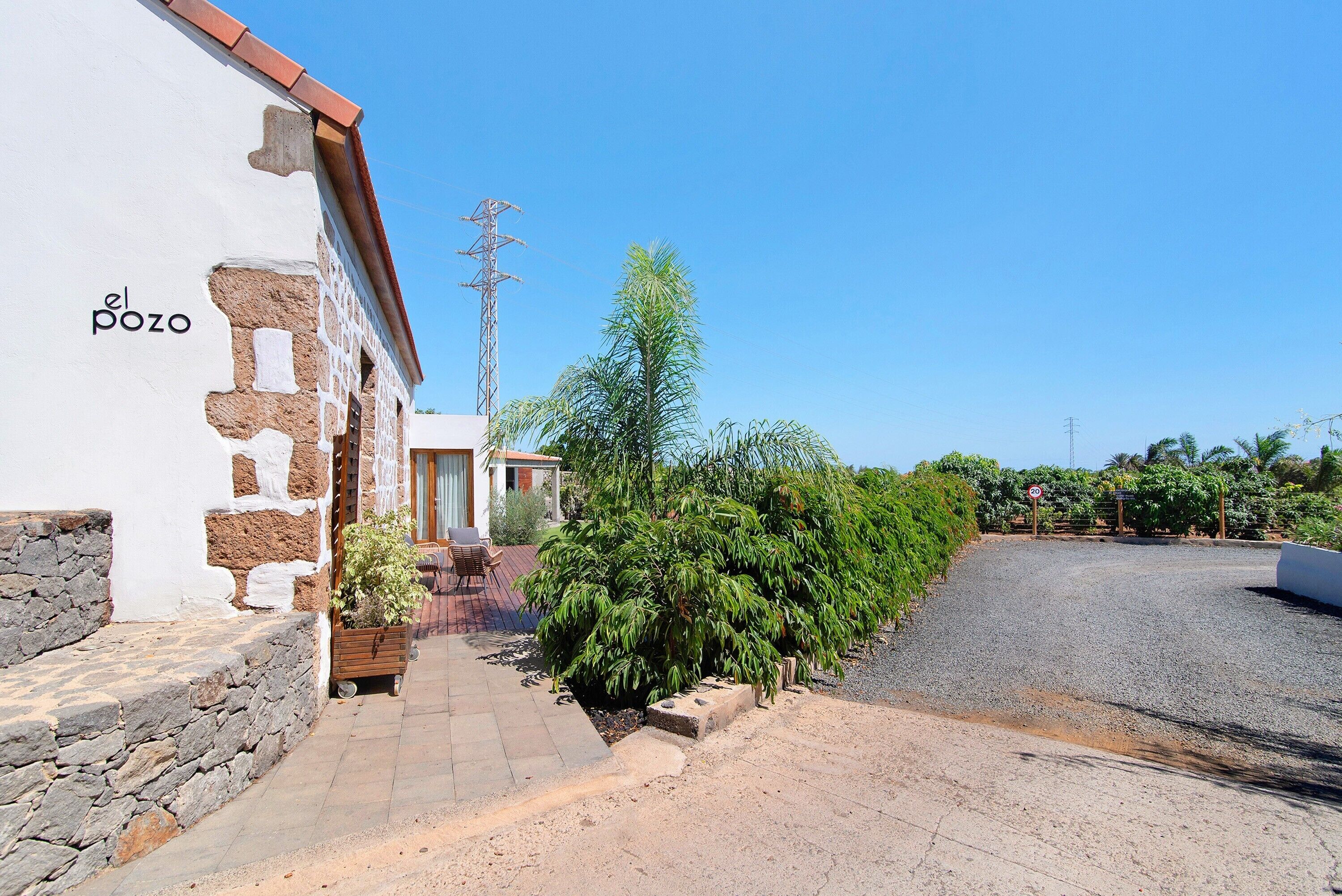 Un edificio con fachada de piedra, un letrero que dice 'el pozo' y un sendero pavimentado.