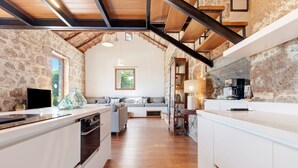 A kitchen with a stone wall, wooden beams, a built-in bench, and a coffee machine.