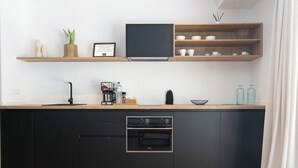 A modern kitchen with a built-in oven, wooden shelves, and a coffee maker. - Country House 'Iris - Finca La Suerte Grande' with Mountain Views and Wi-Fi (Telde)