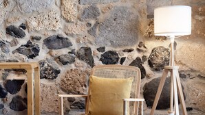 A chair with a cushion, a lamp on a tripod, and a stone wall. - Country House 'Iris - Finca La Suerte Grande' with Mountain Views and Wi-Fi (Telde)