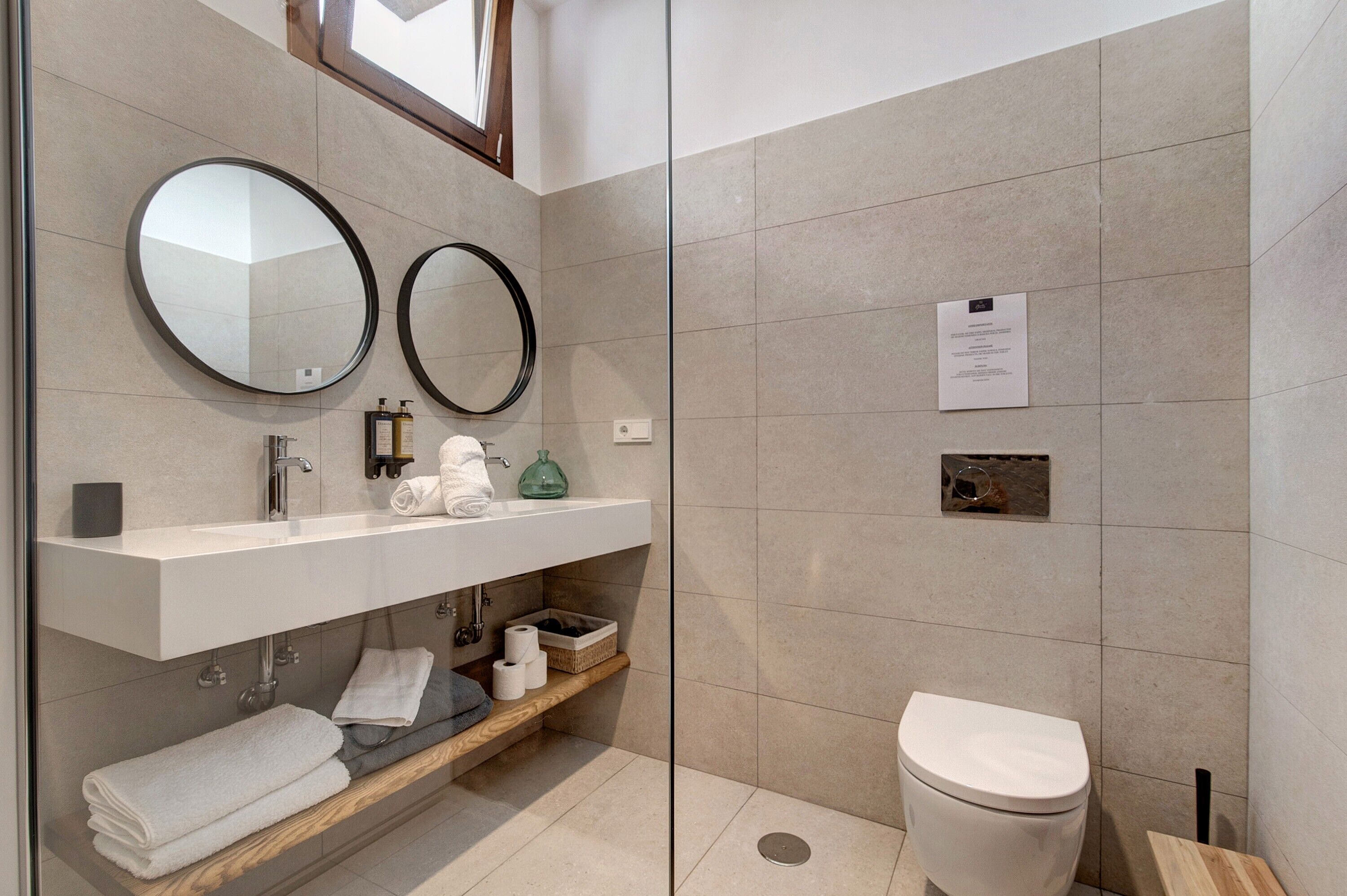 Une salle de bain moderne comprenant un meuble-lavabo, deux miroirs, des toilettes et un espace douche.