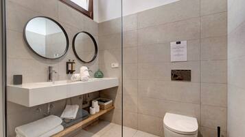 Une salle de bain moderne comprenant un meuble-lavabo, deux miroirs, des toilettes et un espace douche.