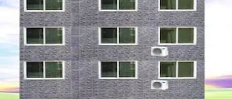 A multi-story building with a consistent window pattern and air conditioning units on the facade.