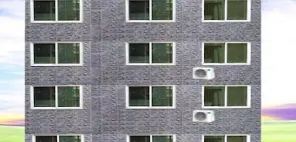 A multi-story building with a consistent window pattern and air conditioning units on the facade.