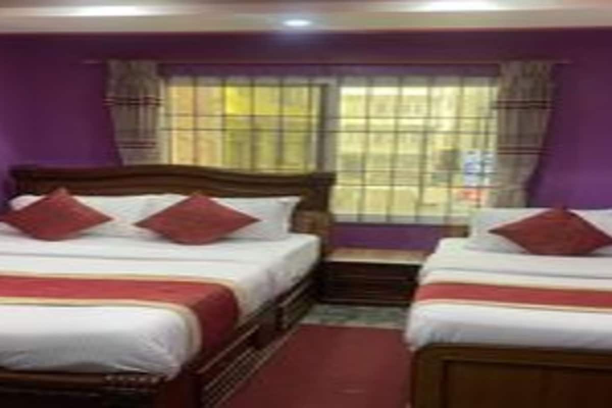 A hotel room with two beds, purple walls, and a window with blinds.
