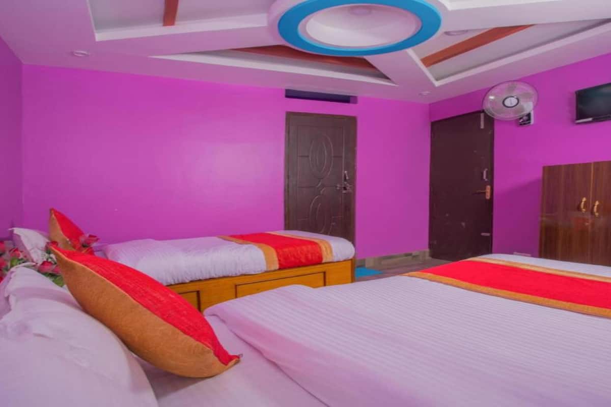 A room with two beds, a wooden wardrobe, and a ceiling fan.