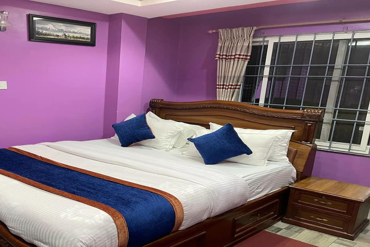 A bedroom with a wooden bed, purple walls, a window with curtains, and a framed picture on the wall.