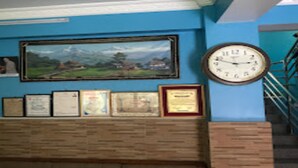 A wall with framed certificates, a large clock, and a landscape painting. - MeroStay 117 Siddhi Binayak Hotel (Tohka)