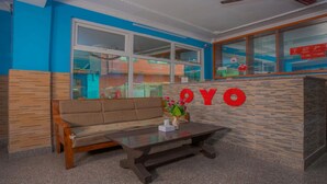 A reception area with a wooden bench, a table with a vase of flowers, and a wall with the word "YOYO" in red letters. - MeroStay 117 Siddhi Binayak Hotel (Tohka)