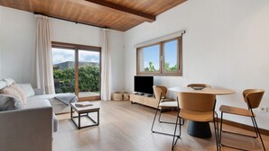 A modern living room with a sofa, coffee table, TV, and dining area with chairs and a table. - Holiday Home 'Musa - Finca La Suerte Grande' with Mountain Views and Private Terrace (Telde)