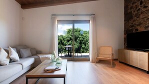 Un salon moderne avec un canapé, une table basse, un téléviseur et un mur en pierre.