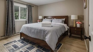 Une chambre à coucher avec un lit, des tables de chevet, une fenêtre avec des rideaux et un tapis.