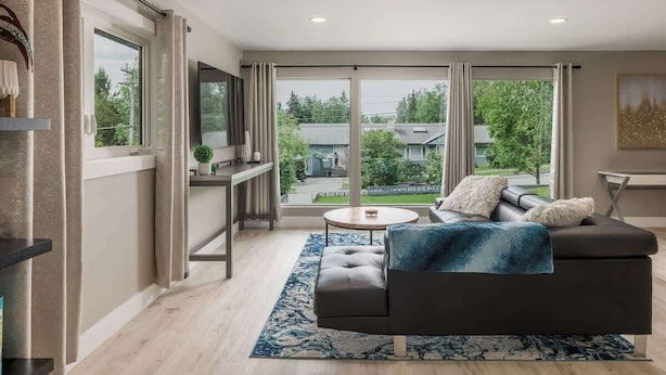 Un salon moderne avec un canapé foncé, une table basse ronde et un tapis bleu.