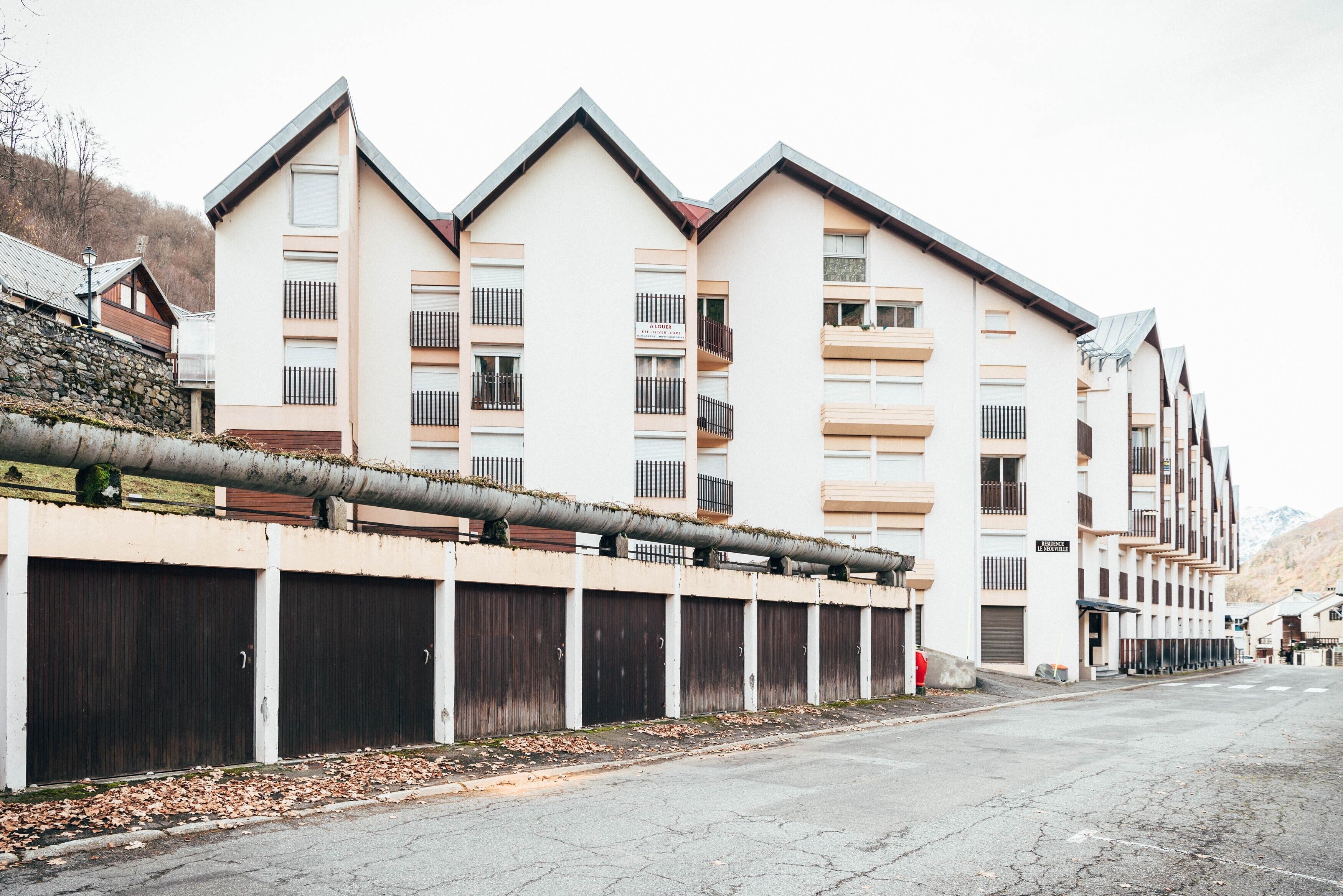 A multi-story hotel with a modern architectural design, featuring balconies and a covered parking area.