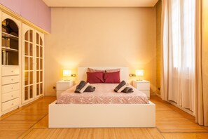 A bedroom with a bed, two bedside tables, a wardrobe, and a window with curtains.