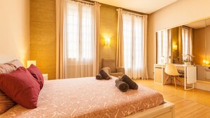 Une chambre d’hôtel avec un lit, un bureau, une chaise et un grand miroir.