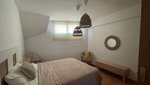 Une chambre à coucher comprenant un lit, une chaise, un banc, une fenêtre et un ventilateur de plafond.