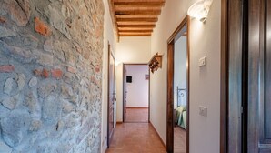 A hallway with a stone wall, wooden ceiling beams, and a tiled floor. - Holiday Apartment "Le Rondini" with Shared Pool, Shared Garden & Wi-Fi (Lamporecchio)