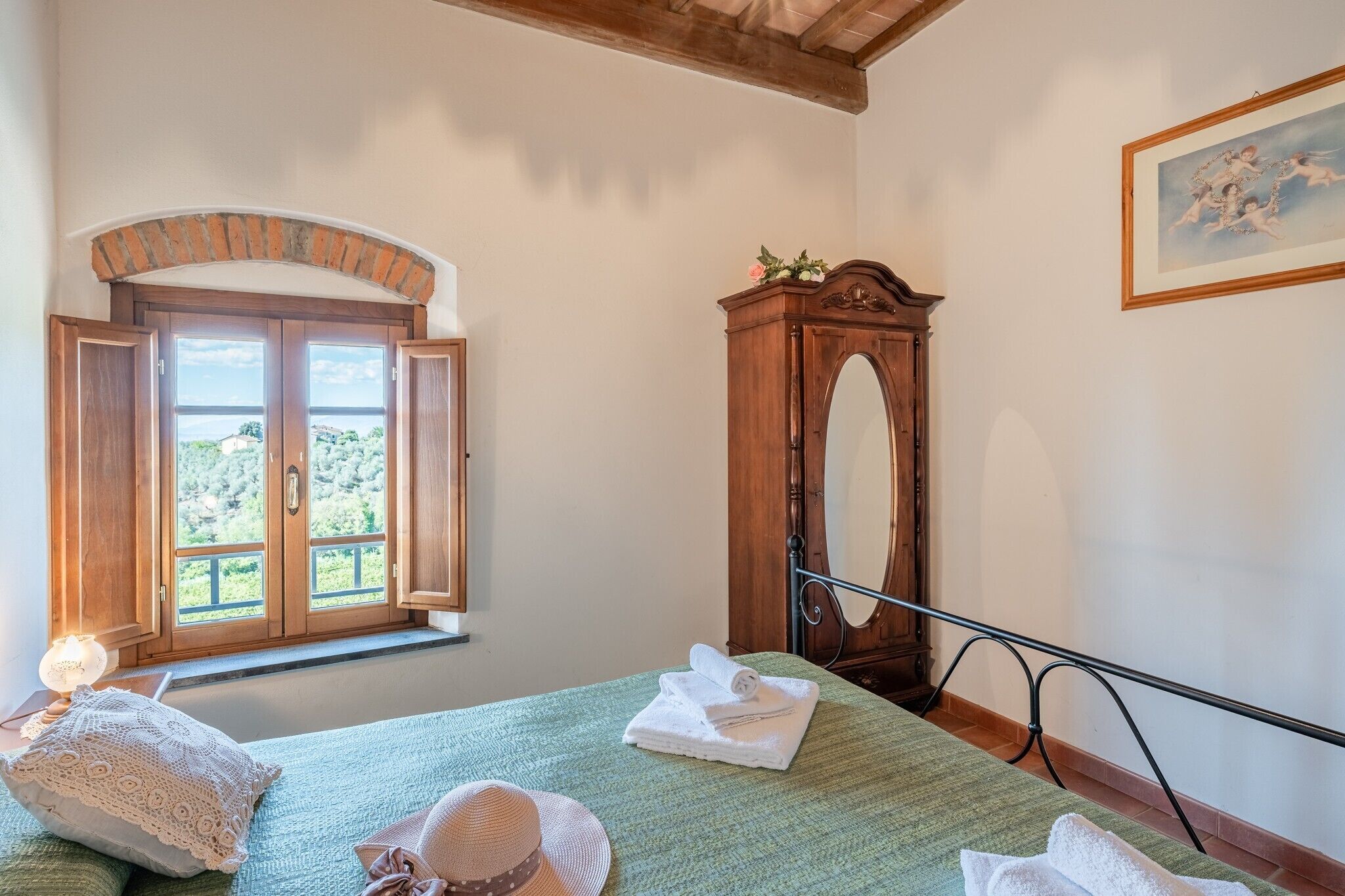Habitació amb un llit, un armari de fusta, una finestra amb persianes obertes i un quadre a la paret.