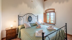 A bedroom with a bed, bedside table, lamp, and window with a view. - Holiday Apartment "Le Rondini" with Shared Pool, Shared Garden & Wi-Fi (Lamporecchio)