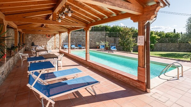 An outdoor pool area with wooden pergolas, lounge chairs, and a stone wall backdrop. - Holiday Apartment "Le Rondini" with Shared Pool, Shared Garden & Wi-Fi (Lamporecchio)
