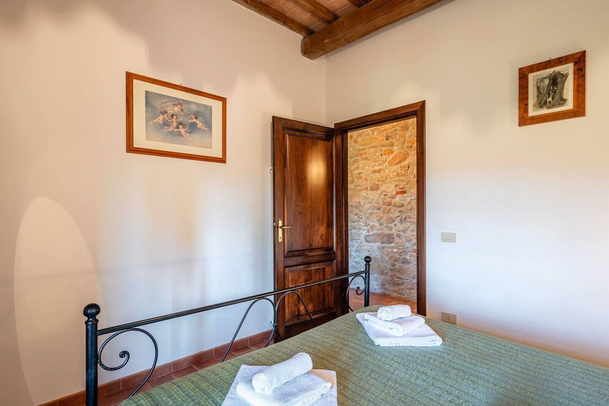 Une pièce avec un lit, une porte et un mur en pierre.