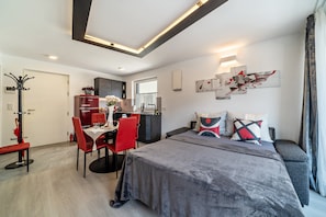 Una camera d'albergo moderna con un letto, un'area ristoro, un angolo cottura e un bagno.