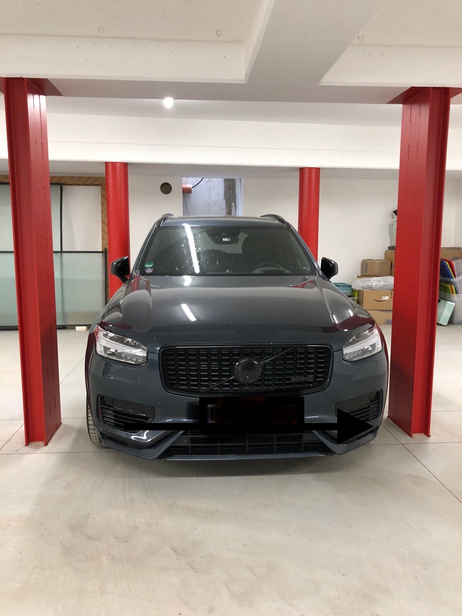 Ein Auto steht in einer Garage mit roten Säulen und einer weißen Decke.