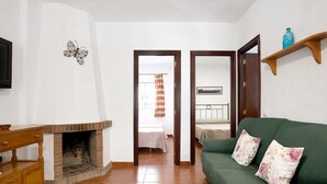 Een woonkamer met een open haard, een groene bank en een houten kast.