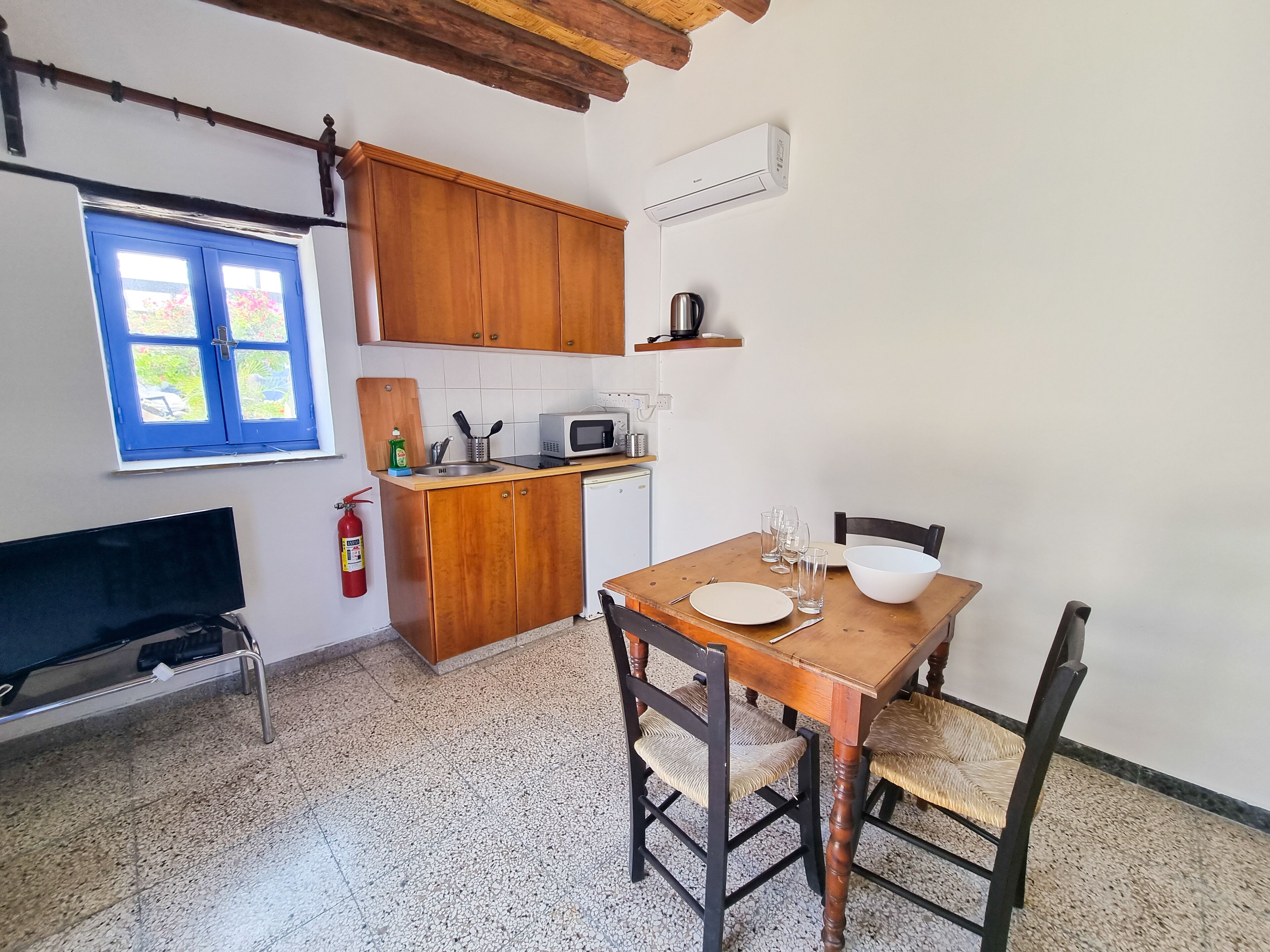 A compact kitchen with wooden cabinets, a microwave, and a dining table set for two.
