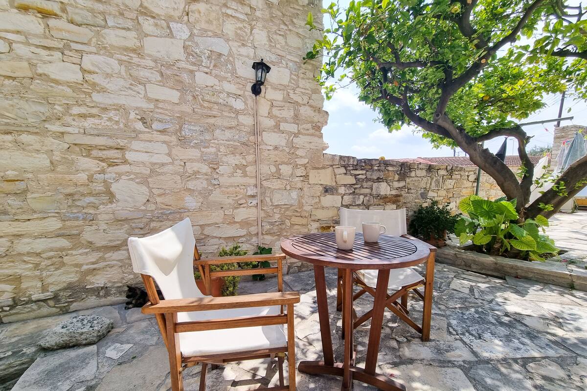 A stone wall, two wooden chairs, a round table, and a hanging light fixture.