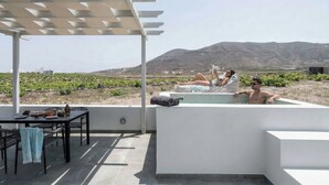 Une terrasse sur le toit avec une pergola, une piscine et une table avec une bouteille et des verres.