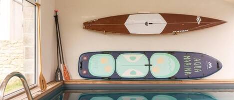 A swimming pool with two surfboards mounted on the wall.