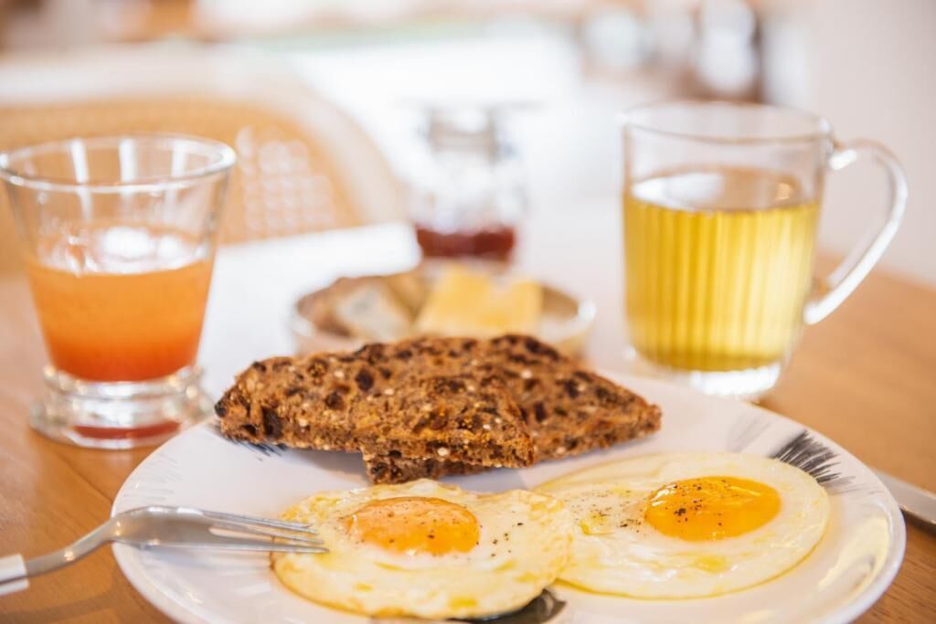 A breakfast plate with eggs, toast, and a glass of orange juice.