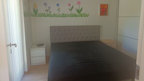 A bedroom with a bed, a nightstand, a small drawer, a wall with a floral mural, and a door. - 3 bedroom private vacation home in silkeborg (Silkeborg)