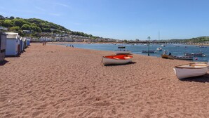 Une plage avec plusieurs bateaux, un ciel dégagé et une ville qui se profile à l’horizon.