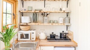 Une cuisine avec des étagères en bois, un four à micro-ondes, une bouilloire et un évier.