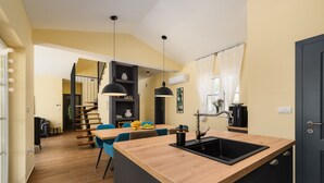 A modern kitchen with a wooden island, black cabinets, and a dining area with blue chairs. - Luxury Villa Istra Maruzini with private pool in Rovinj,  Istria (Maružini)