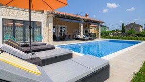 A swimming pool with lounge chairs and an umbrella, surrounded by stone walls and a tiled roof. - Luxury Villa Istra Maruzini with private pool in Rovinj,  Istria (Maružini)