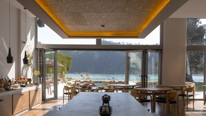 A modern kitchen with a large island, wooden furniture, and a view of the sea. - Malates Slow Boutique Hotel (Foz)