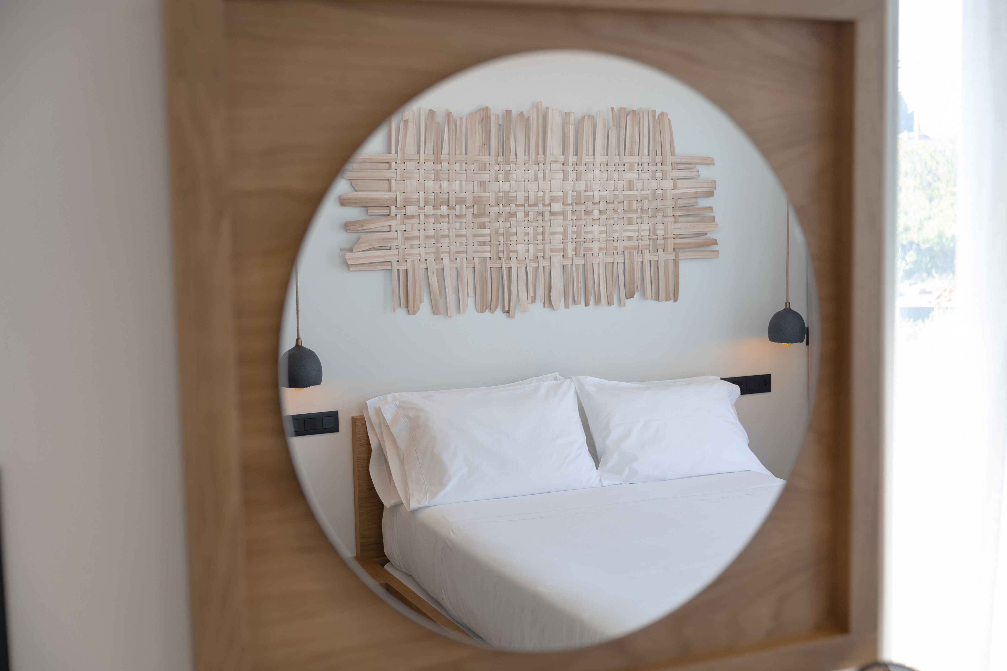 A bed with white linens, a wooden headboard, and two bedside lamps.